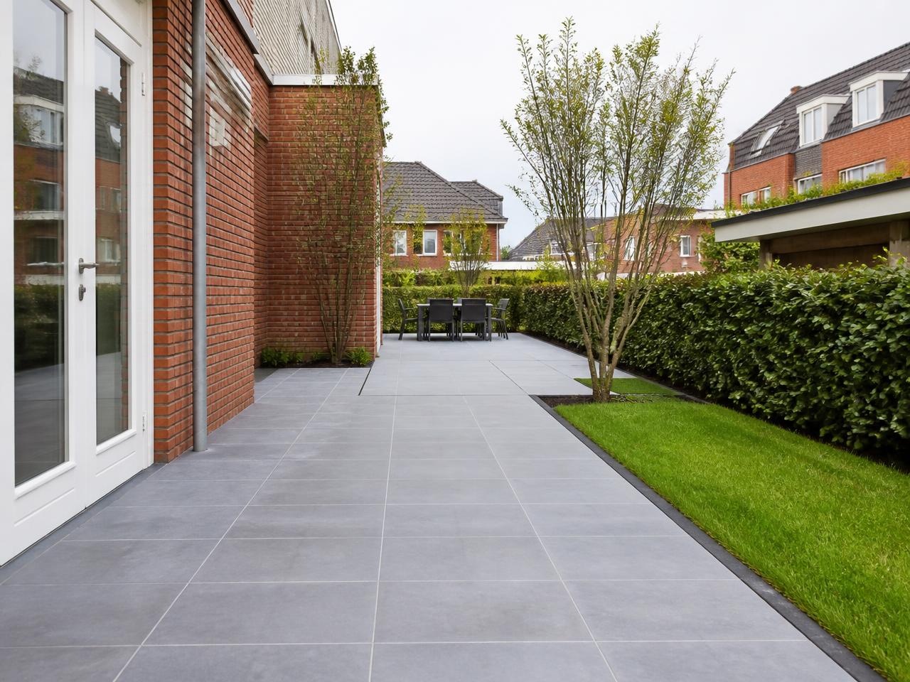 Nieuw aangelegd keramisch terras met gazon en beukenhaag in een tuin in Almere